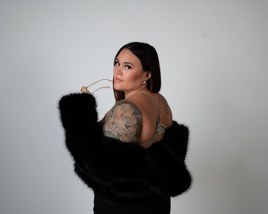 Woman looking over shoulder wearing luxury lingerie bra with a black fur coat off shoulders